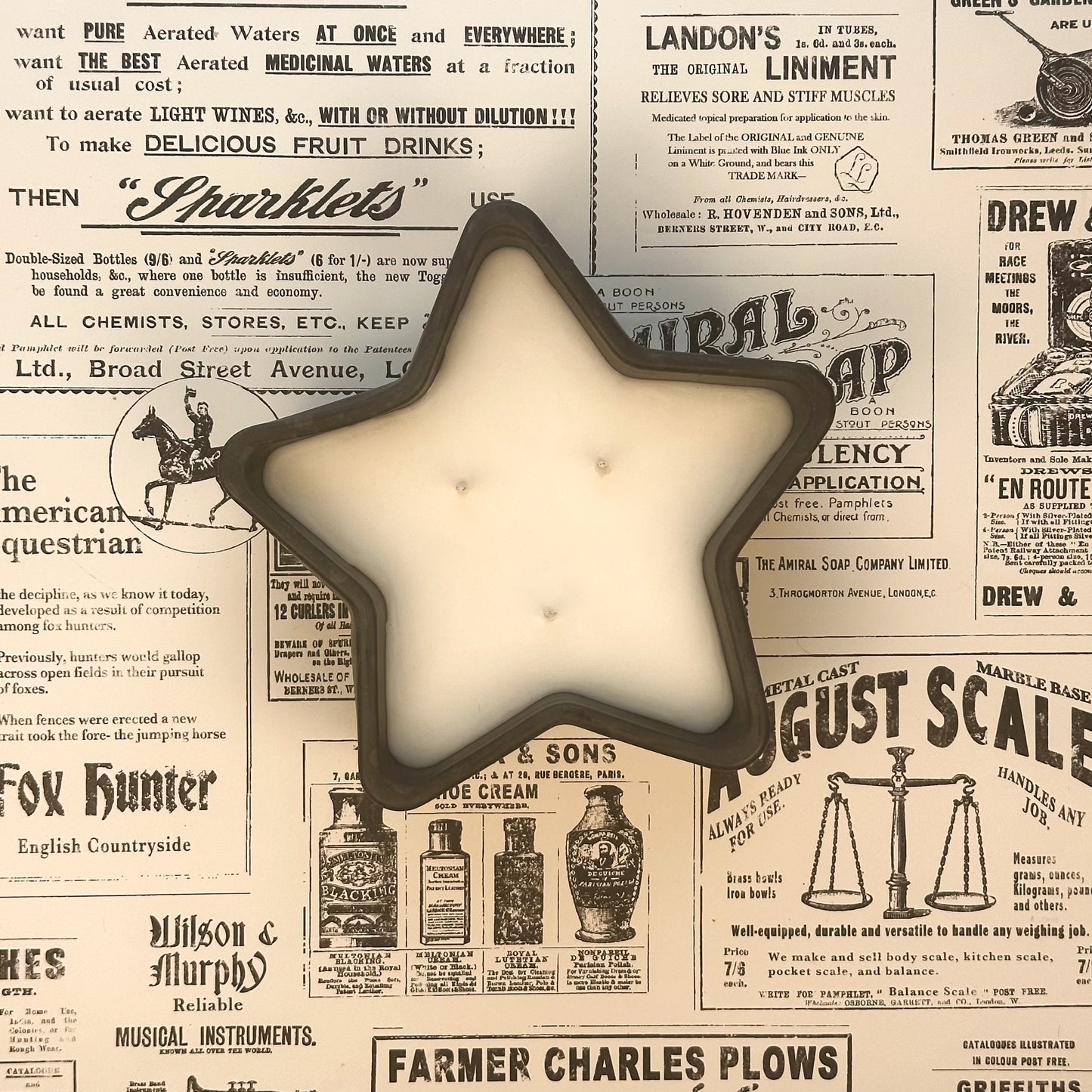 Black concrete star shaped three wick candle on an old newspaper background.