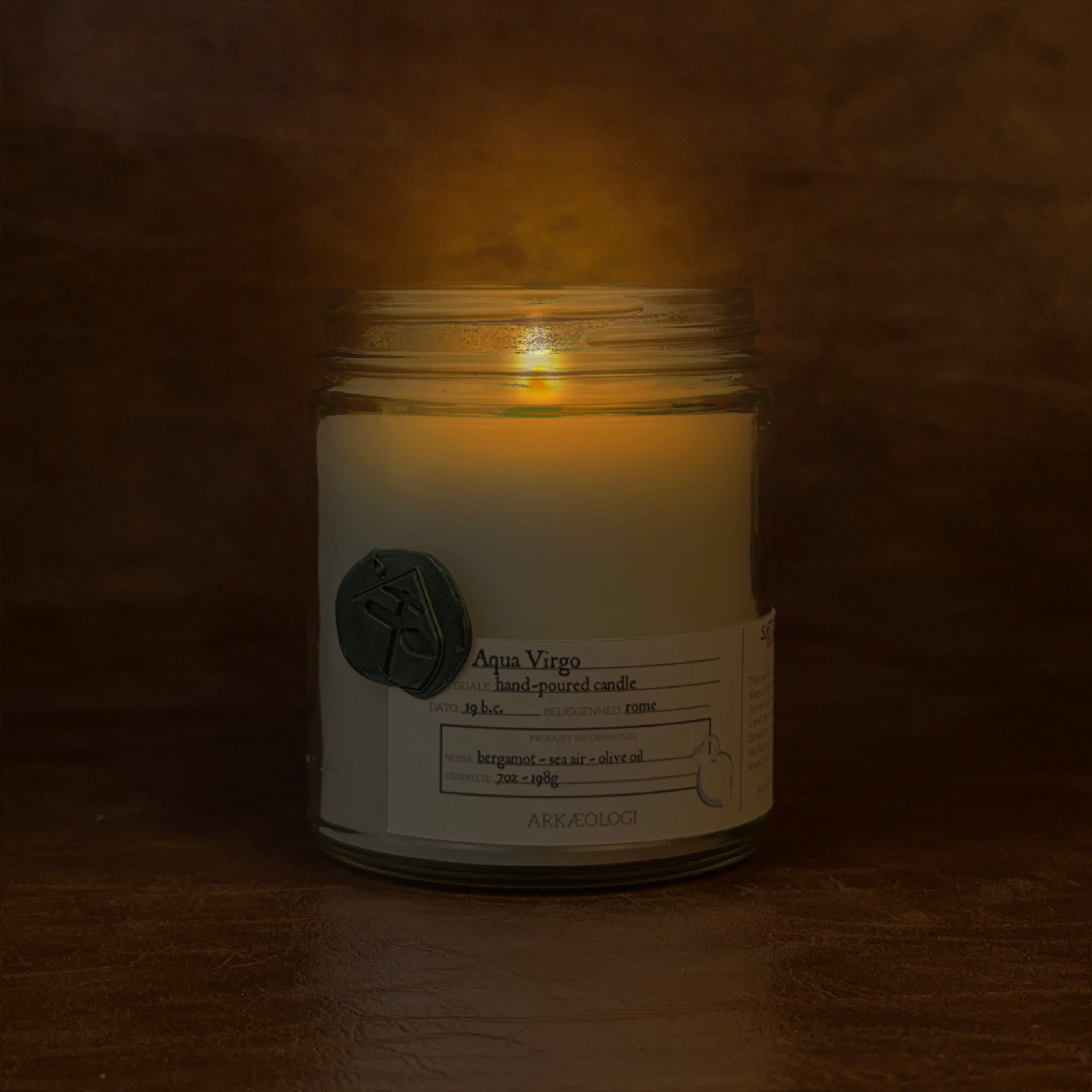 Lit Aqua Virgo candle jar on map background
