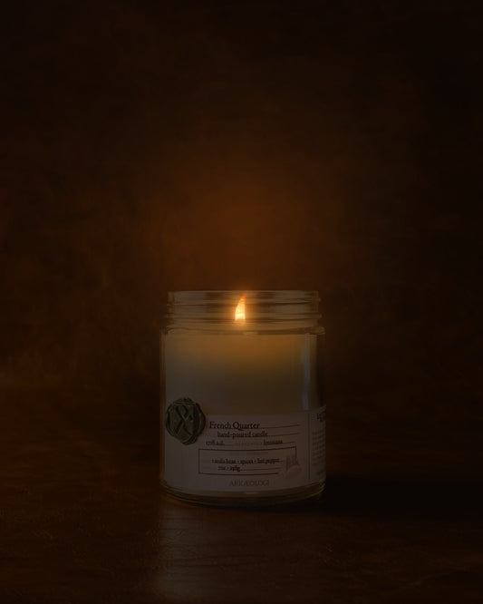 Lit French Quarter in clear jar with green wax seal and white label inspired by artifact tag on leather background