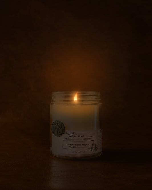 Lit Myrkviðr in clear jar with green wax seal and white label inspired by artifact tag on leather background