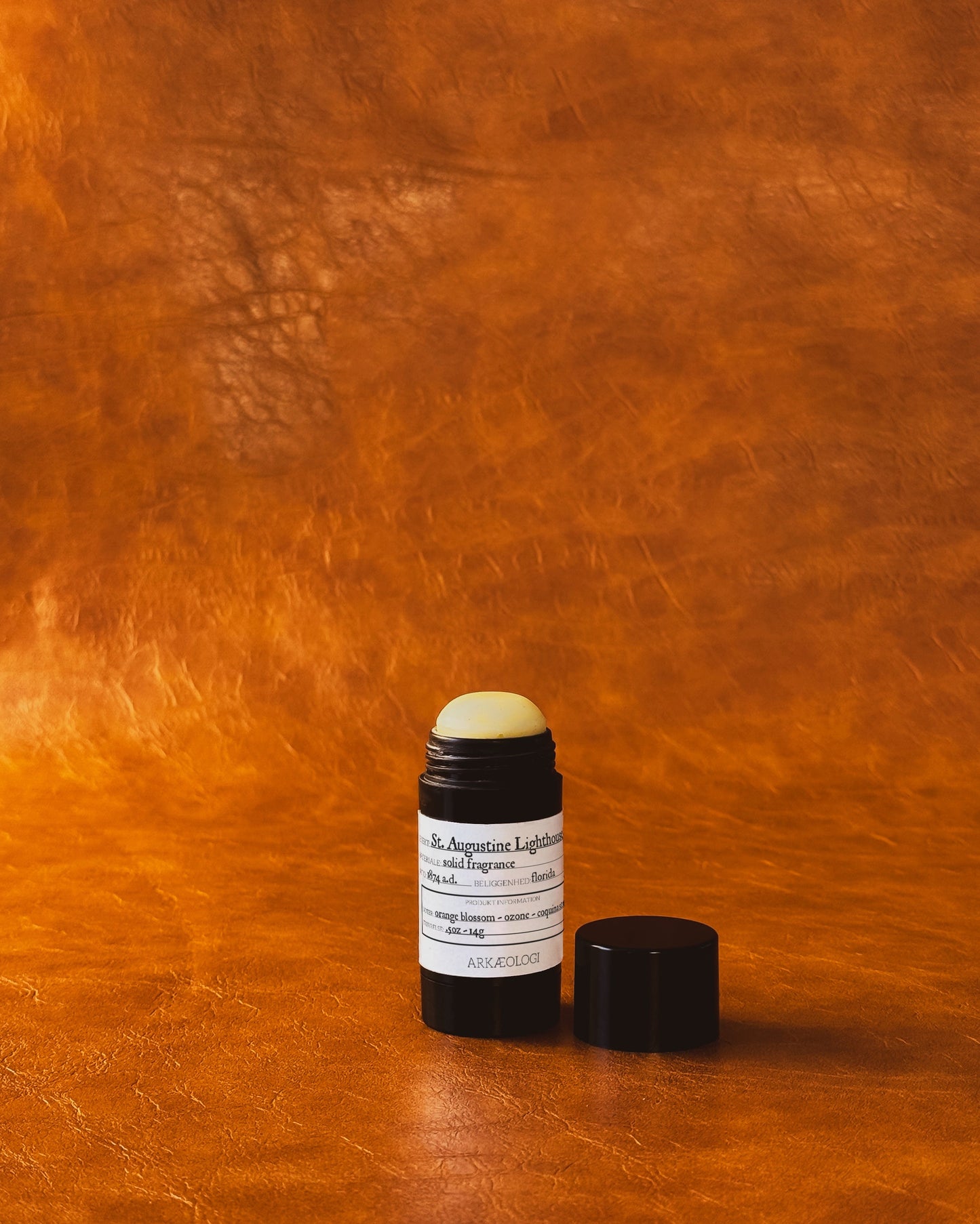 Saint Augustine Lighthouse Solid Fragrance in black tube on leather background.