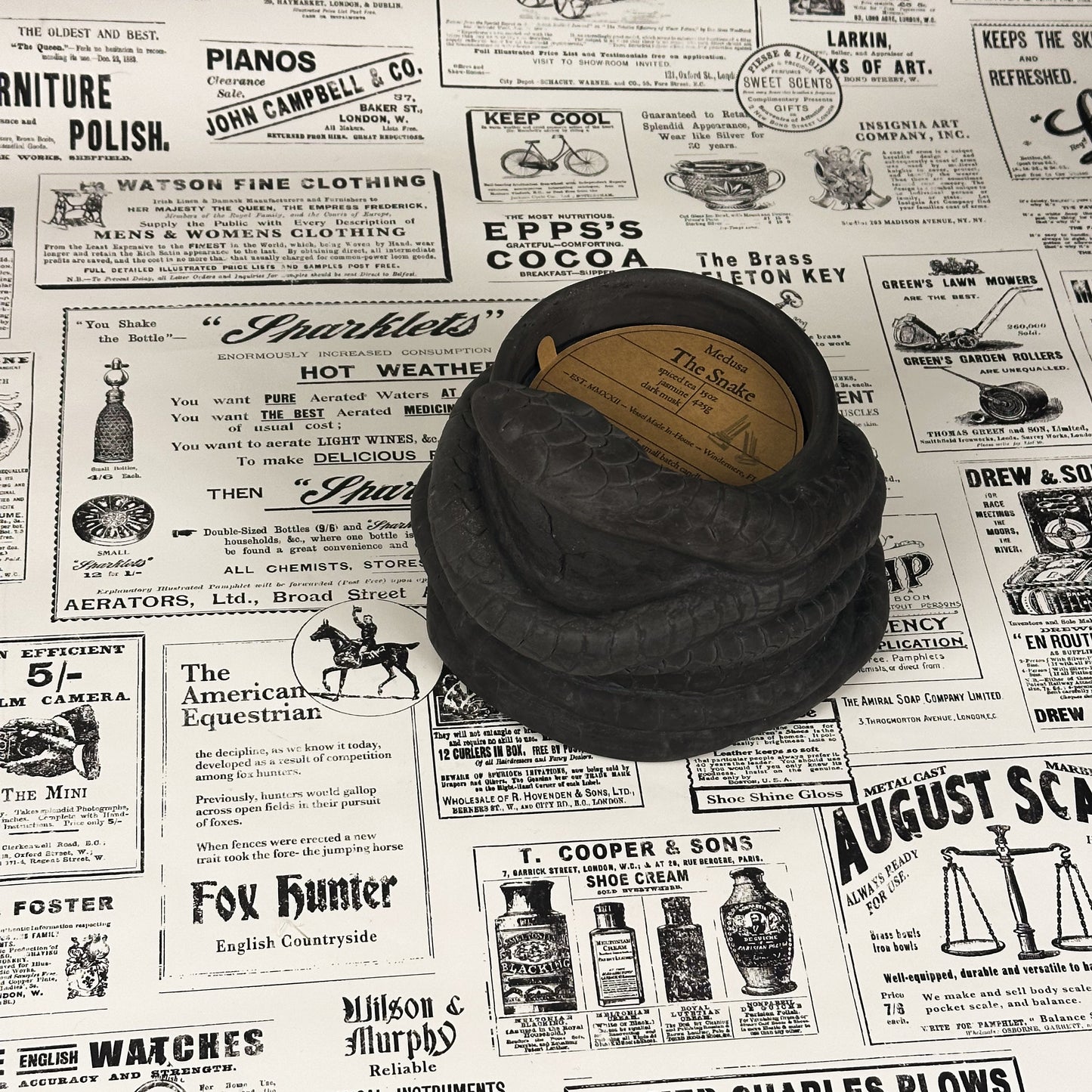 Black concrete snake candle on vintage newspaper background