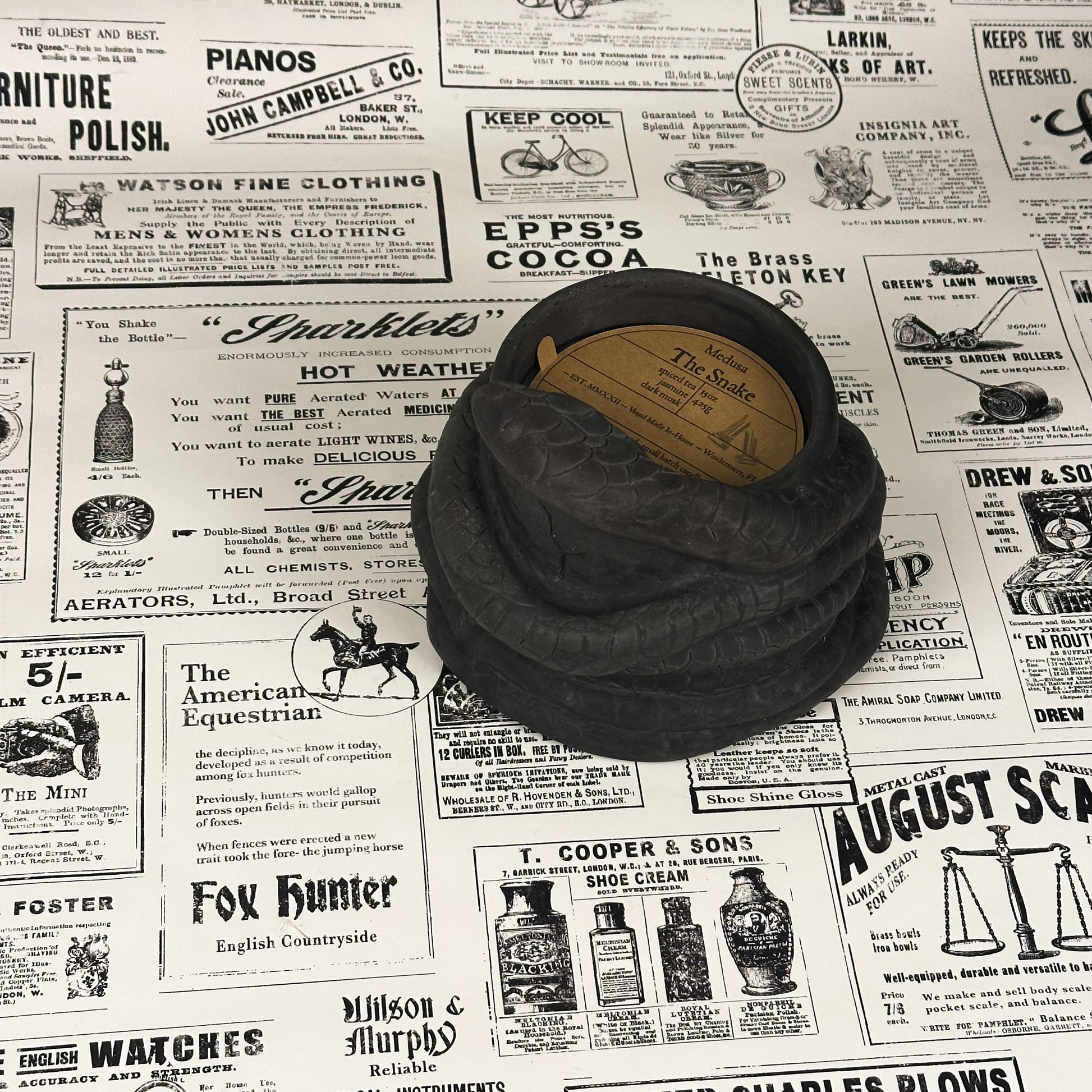 Black concrete snake candle on vintage newspaper background