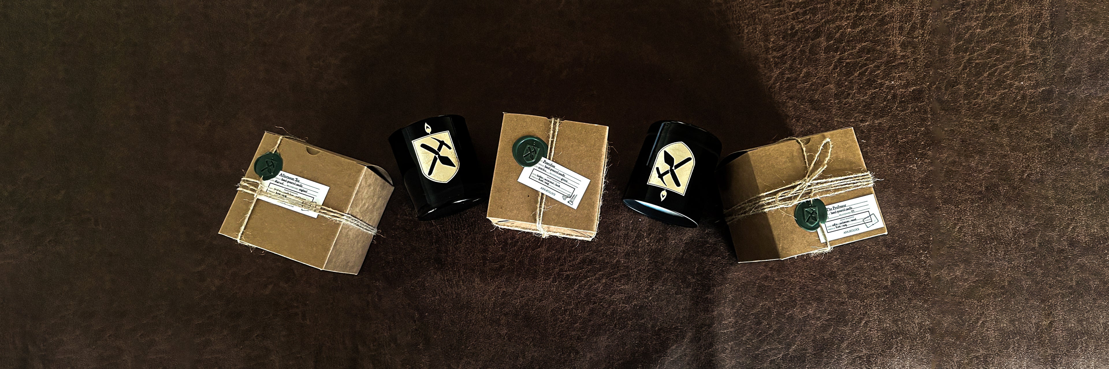 alternating Kraft paper boxes and black glass candles on leather background