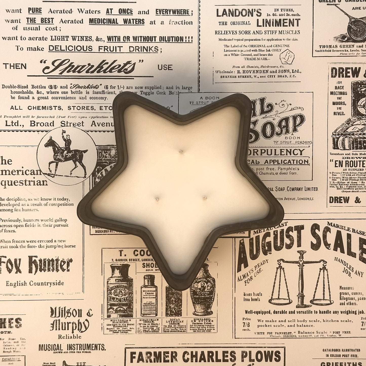 Black concrete star shaped three wick candle on an old newspaper background.