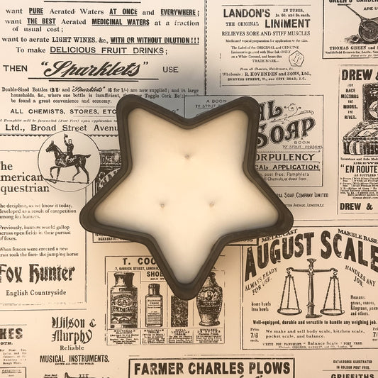 Black concrete star shaped three wick candle on an old newspaper background.